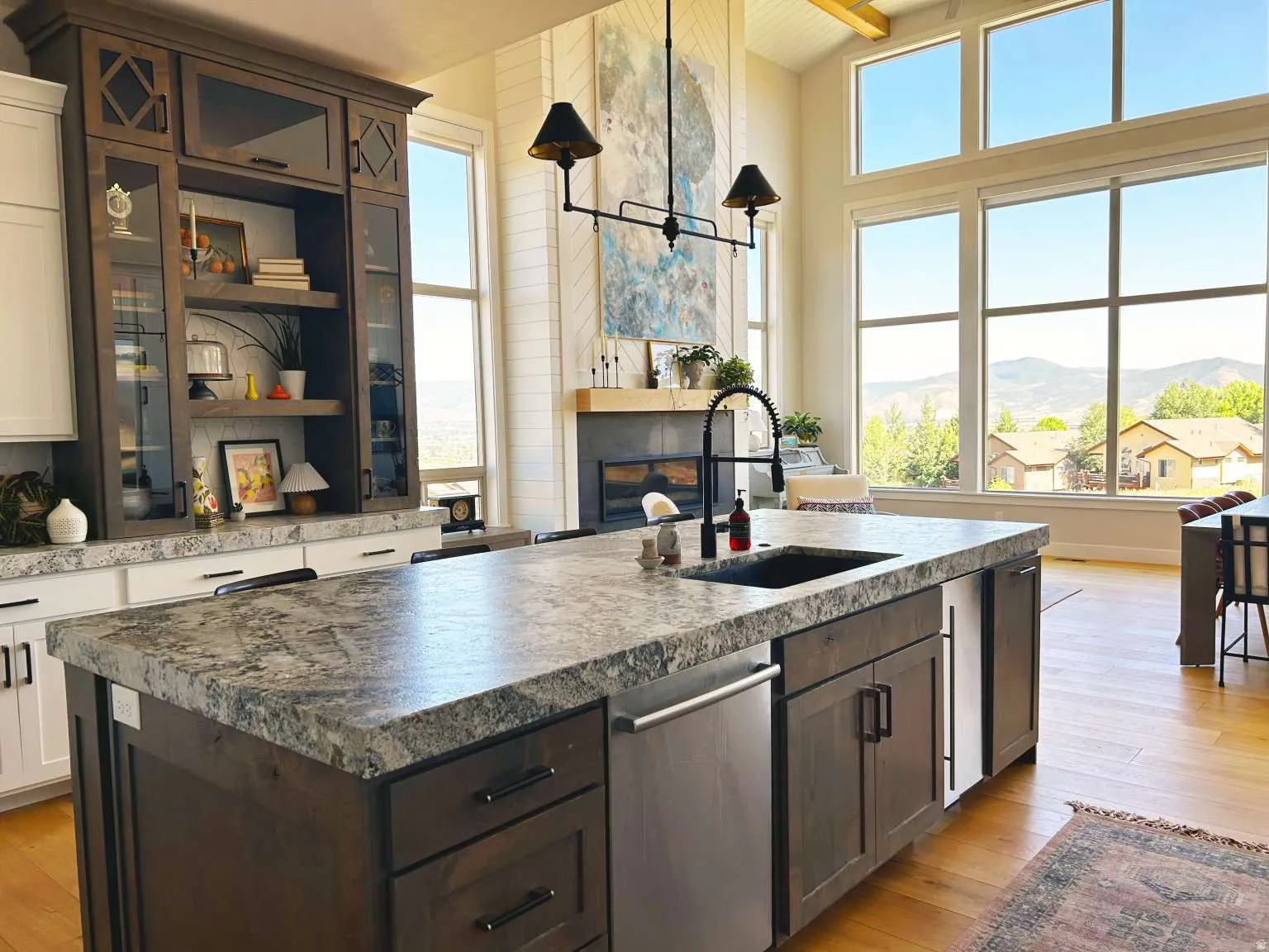 Kitchen island featuring a dark wood-finish base with a speckled countertop, integrated sink, and gooseneck faucet