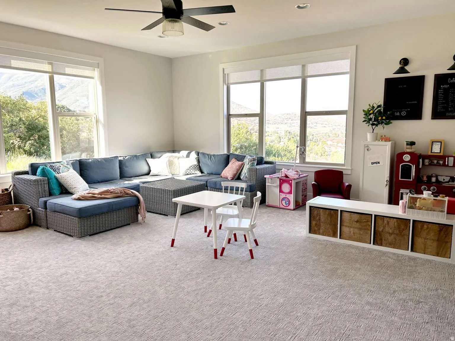 Spacious room with light-colored carpeting, large windows offering natural scenery, a ceiling fan, and recessed lighting