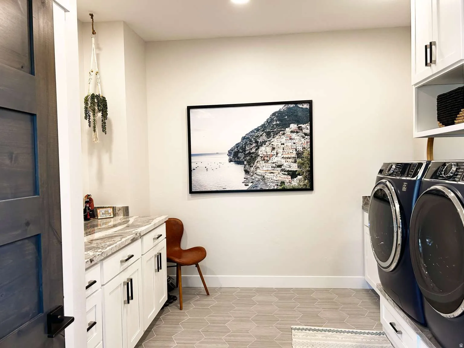 Laundry space featuring white cabinetry with dark hardware, a light-toned countertop, and hexagonal floor tiling