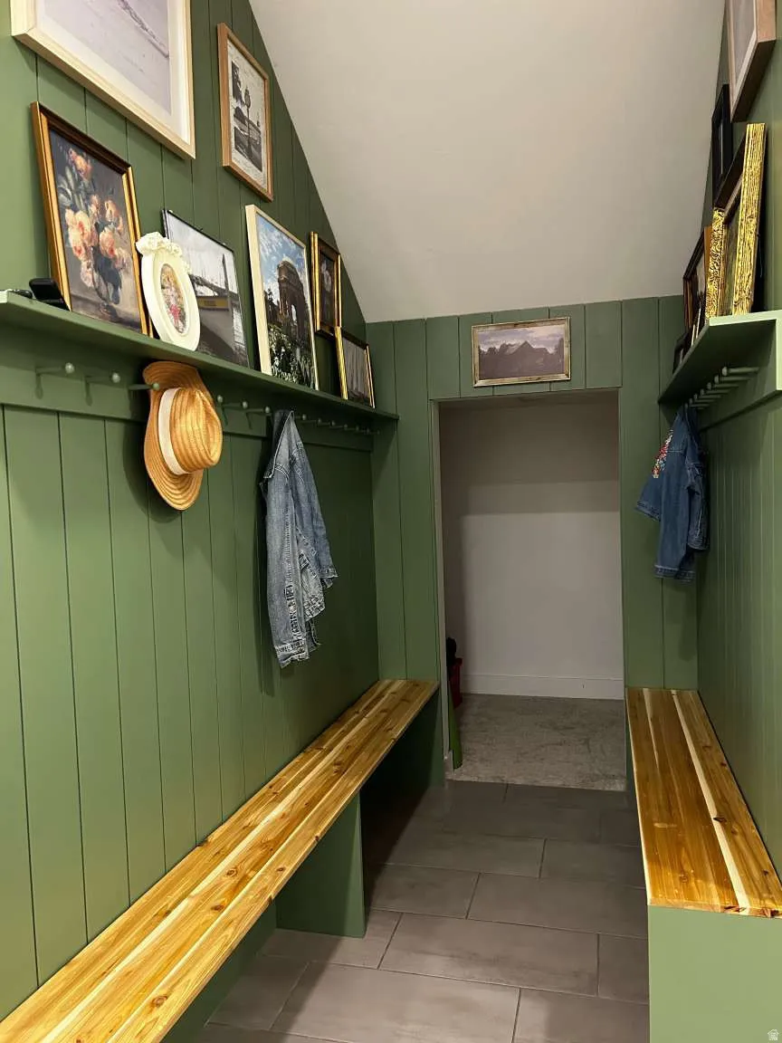 Entryway featuring board and batten paneling in a rich green hue, complemented by light wood-finish benches
