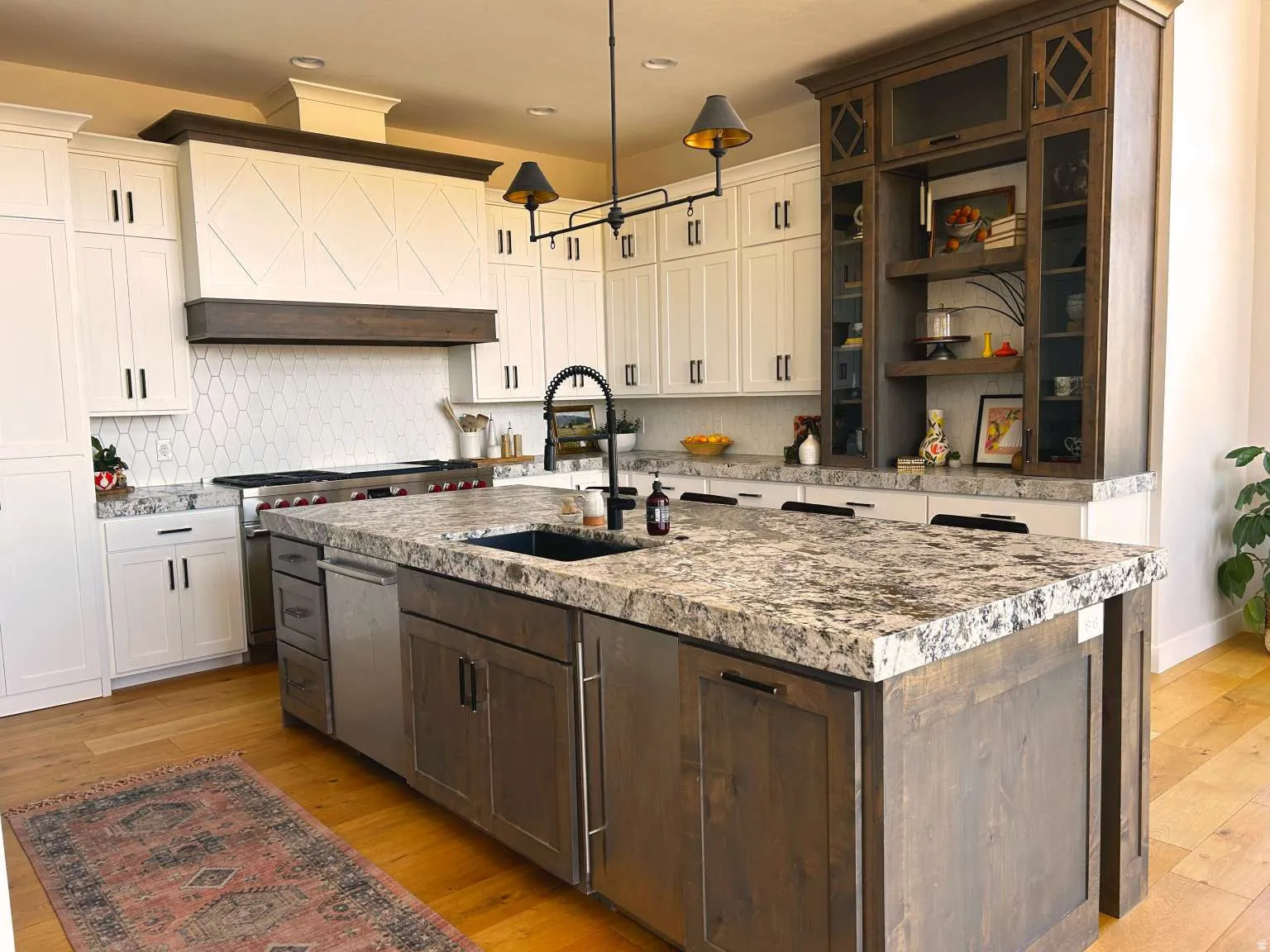 Kitchen island featuring a large undermount sink, a dishwasher, and a stone countertop