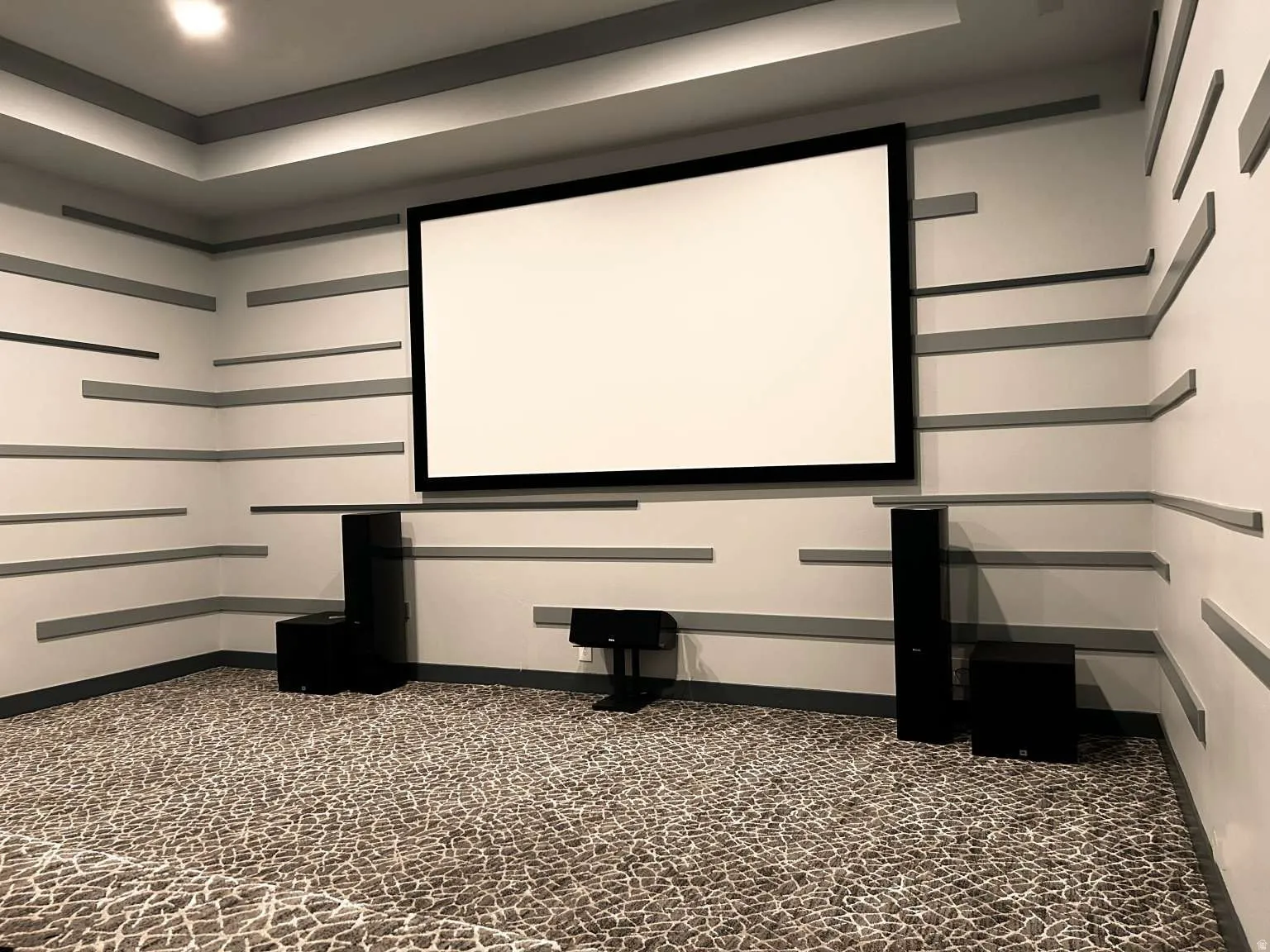 Dedicated media room featuring a large projection screen, recessed lighting, and a tray ceiling