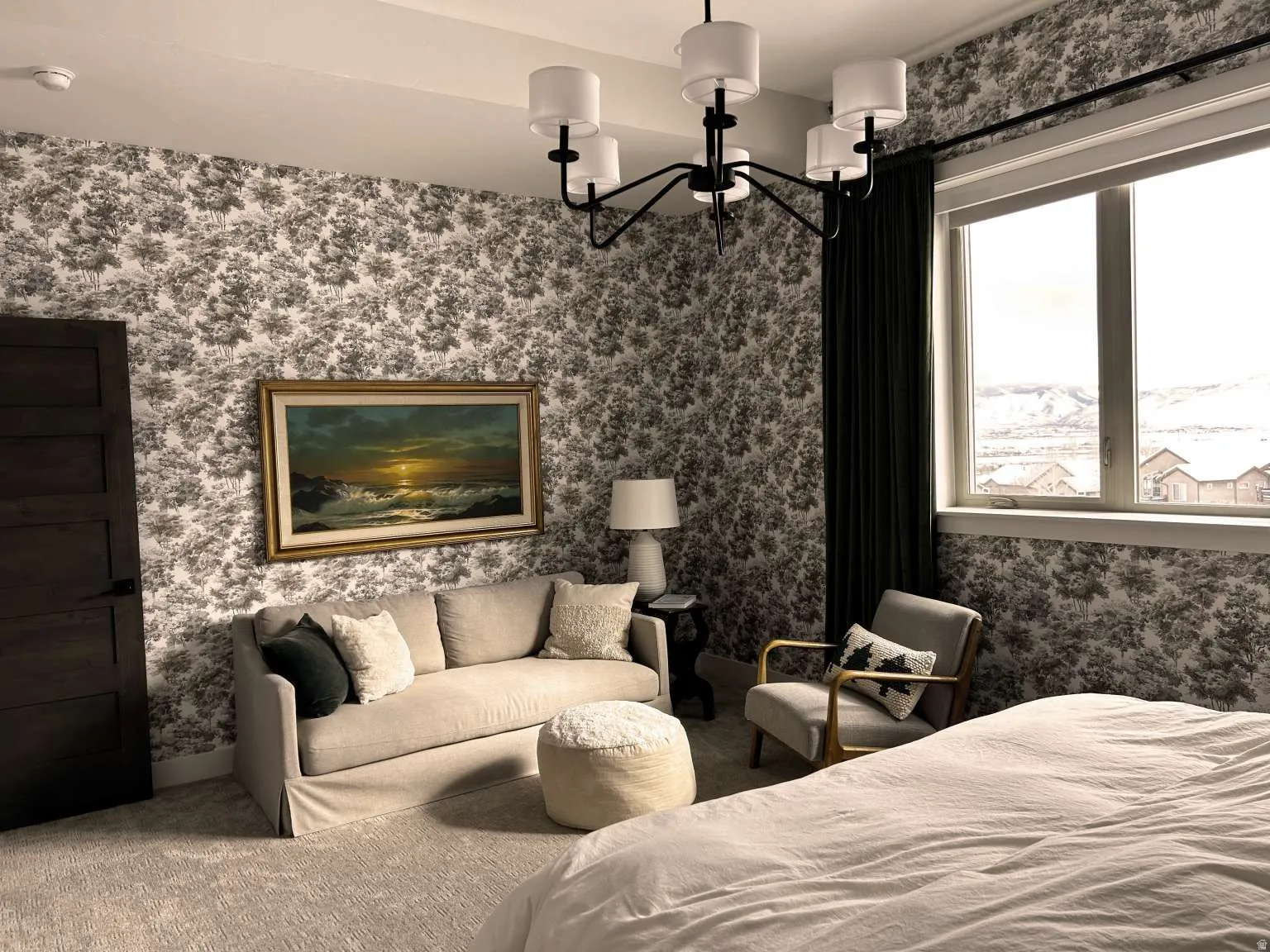 Bedroom featuring patterned wall covering, a large window with mountain scenery, a dark wood-finish door, and recessed lighting