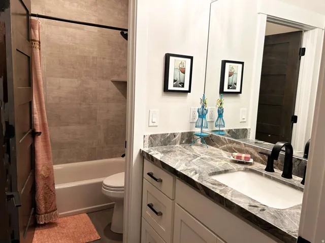 Bathroom featuring a contemporary vanity with a stone countertop, an undermount sink, and a matte black faucet