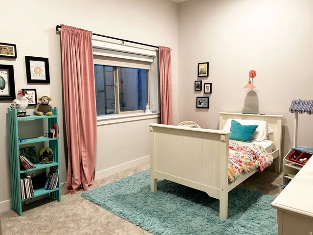 Bedroom featuring light gray wall paint, a window with white trim, and a wall-mounted light fixture