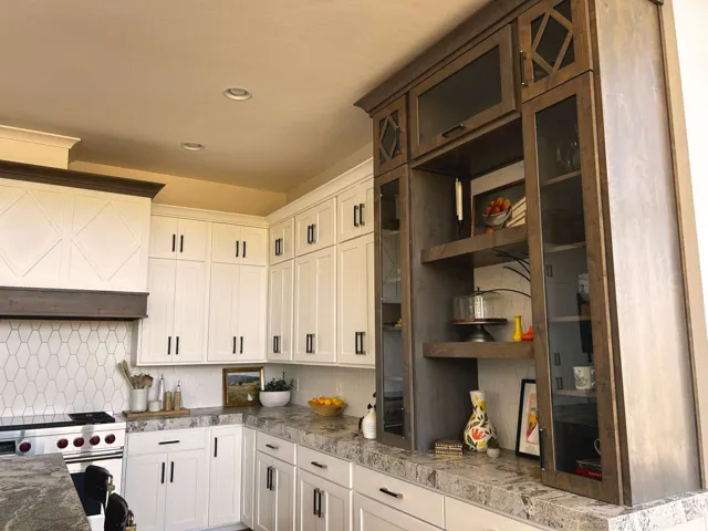 Kitchen featuring white cabinetry and dark wood-finish built-ins with glass-front doors