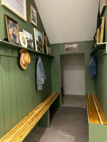 Entryway featuring board and batten paneling in a rich green hue, complemented by light wood-finish benches