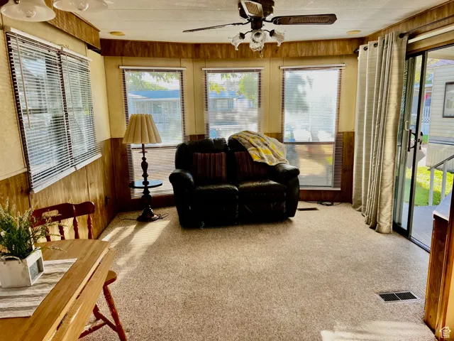 Sunroom featuring wooden walls, carpet flooring, and wainscoting