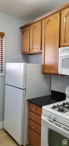 Unit # 3 Kitchen featuring white appliances, brown cabinets, dark stone countertops, and light tile patterned floors