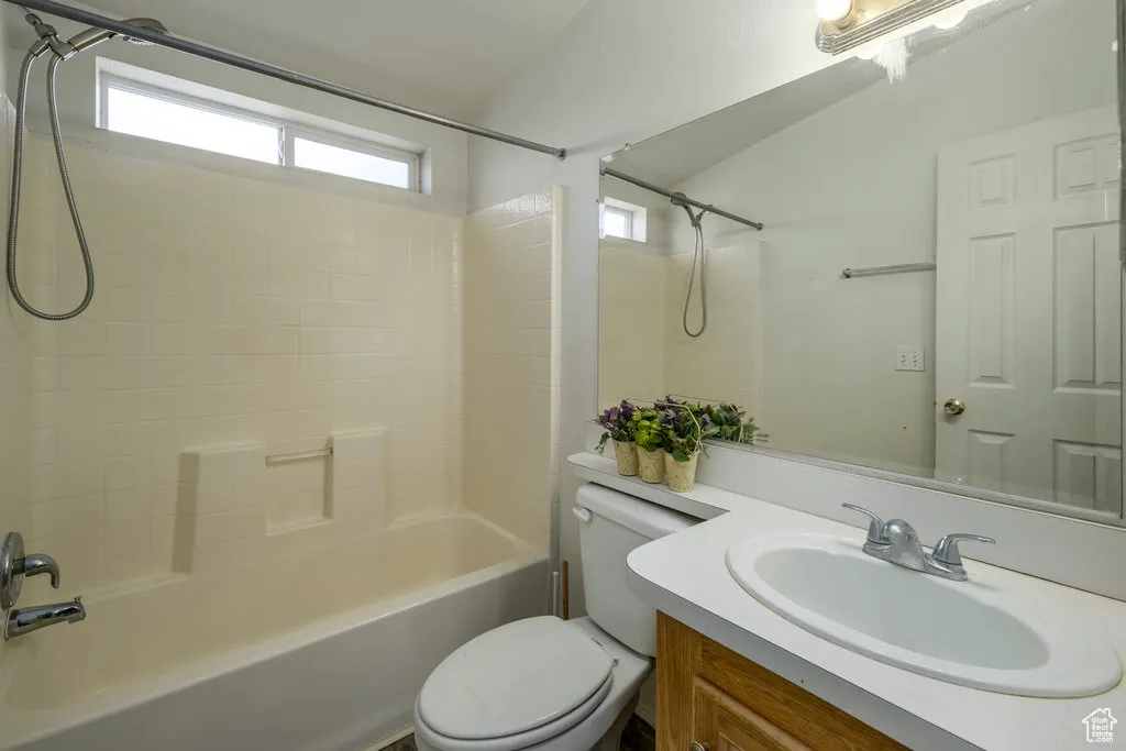 Bathroom featuring vanity, toilet, vaulted ceiling, and shower / bathing tub combination