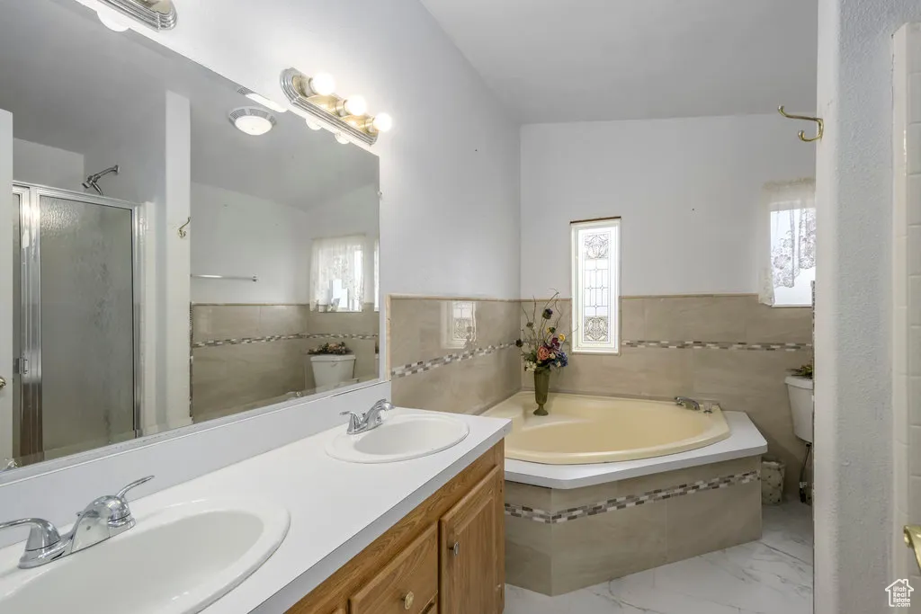 Bathroom featuring a sink, a bath, tile walls, and toilet