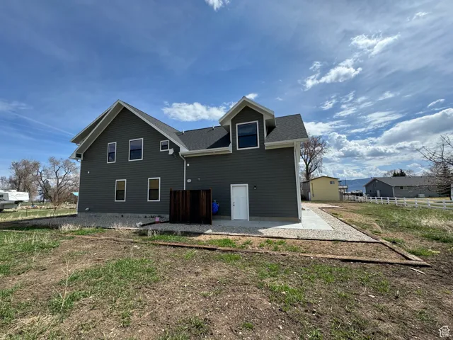 Rear view of house with a shingled roof, a patio area, and fence