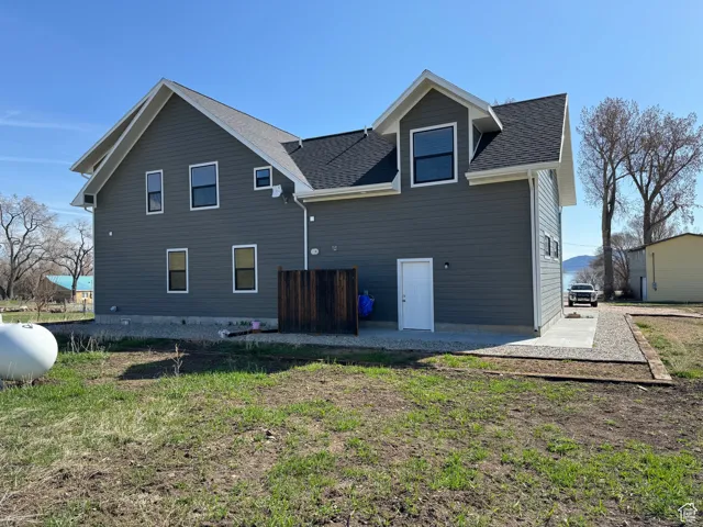 Back of house with patio, roof with shingles and a lawn