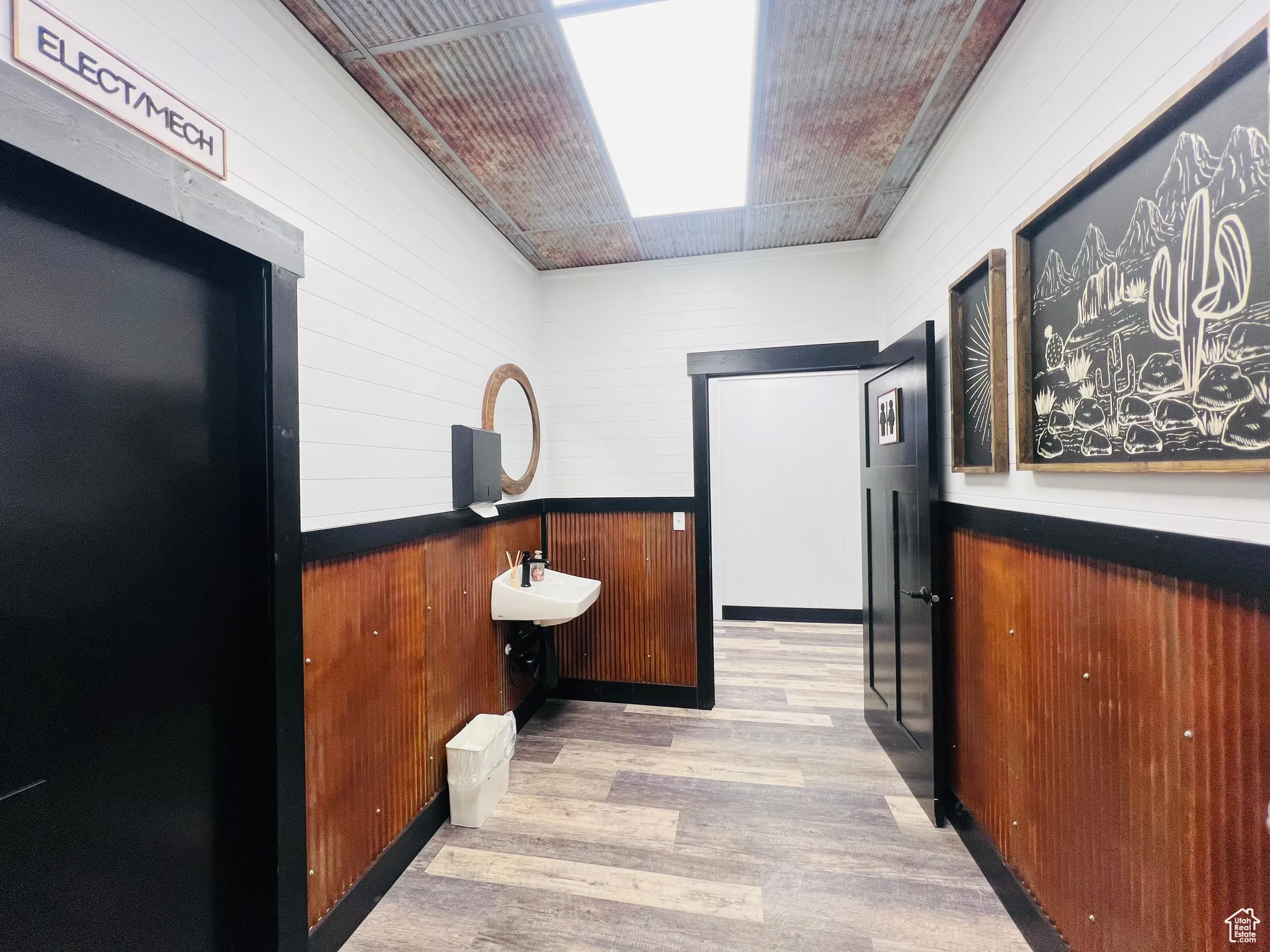 Hall with wooden walls, a sink, and light wood-style floors