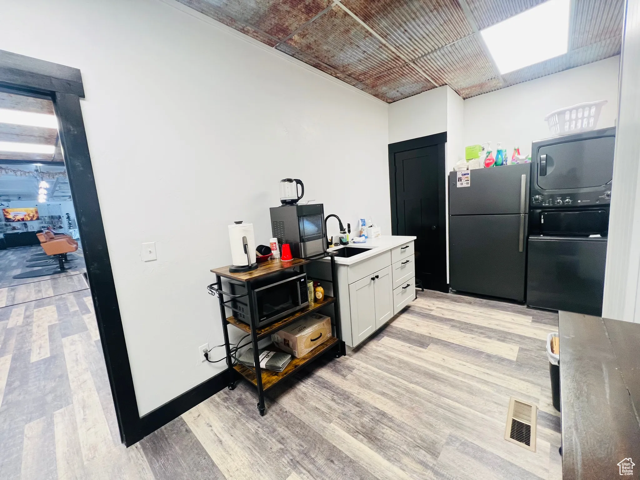 Kitchen featuring freestanding refrigerator, visible vents, a sink, and light wood finished floors