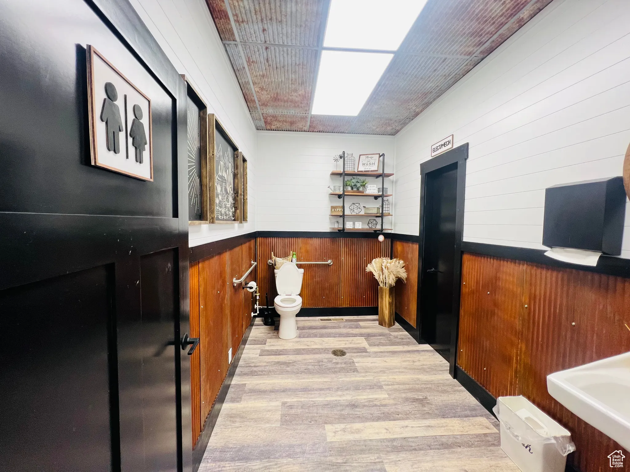 Bar with light wood-style flooring, wooden walls, and wainscoting