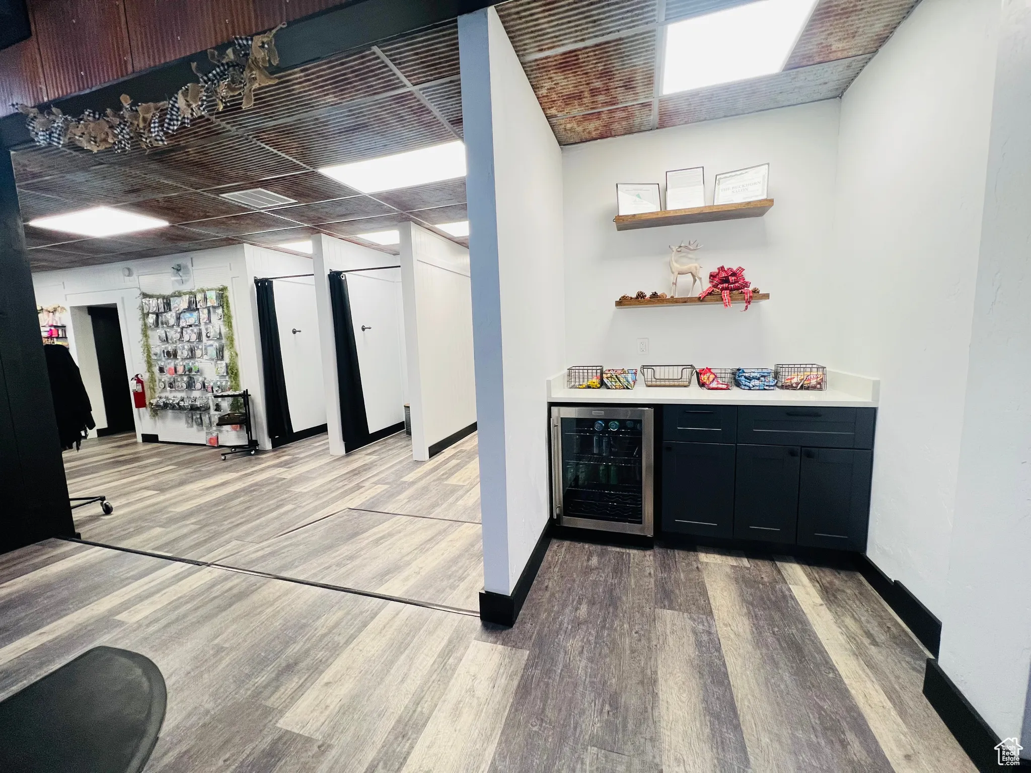 Bar with beverage cooler, baseboards, a bar, and light wood finished floors