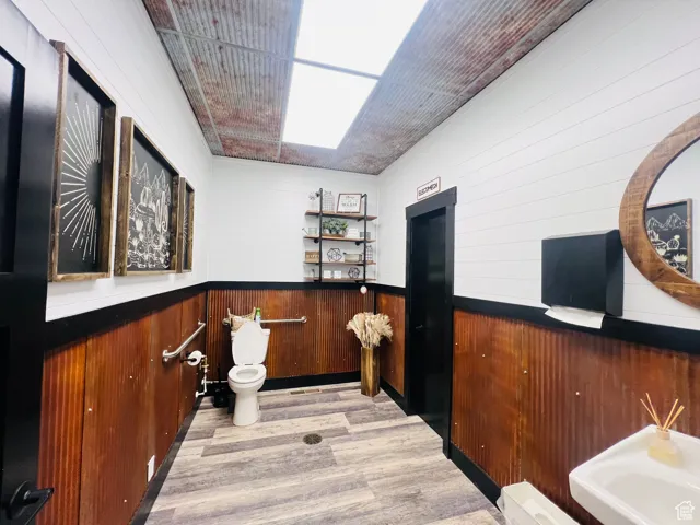 Bar featuring wainscoting, light wood-type flooring, and wooden walls