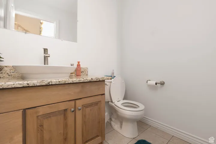 Bathroom featuring toilet, tile patterned flooring, baseboards, and vanity