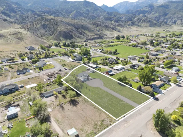 Aerial perspective of suburban area with a mountain backdrop and property parcel outlined