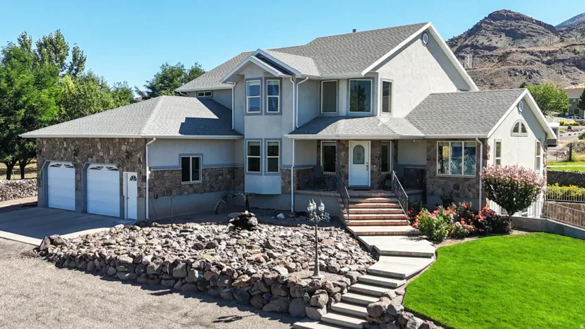 View of front facade with stone siding, stucco siding, a porch, and stairway