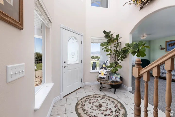 Entrance foyer with light tile patterned flooring, stairs, and arched walkways