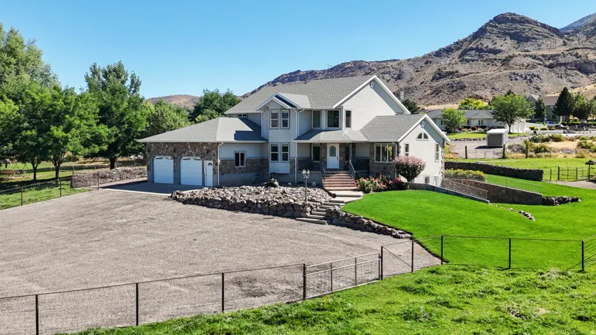 View of front of property featuring a mountain view, stone siding, covered porch, driveway, and a garage