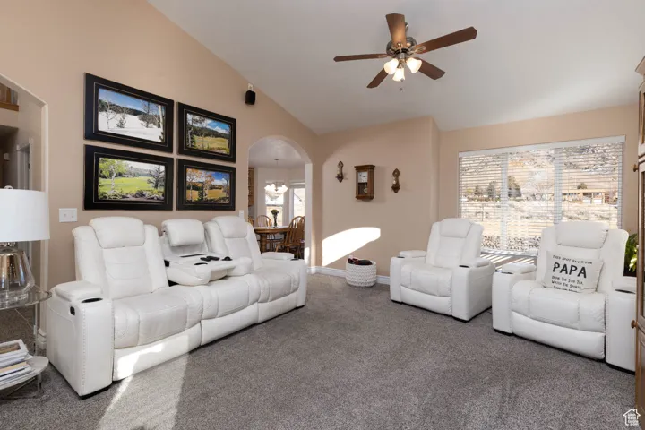 Living room featuring high vaulted ceiling, baseboards, arched walkways, and a ceiling fan