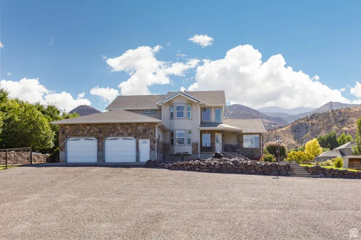 View of front of property featuring asphalt driveway, a garage, a mountain view, a shingled roof, and covered porch