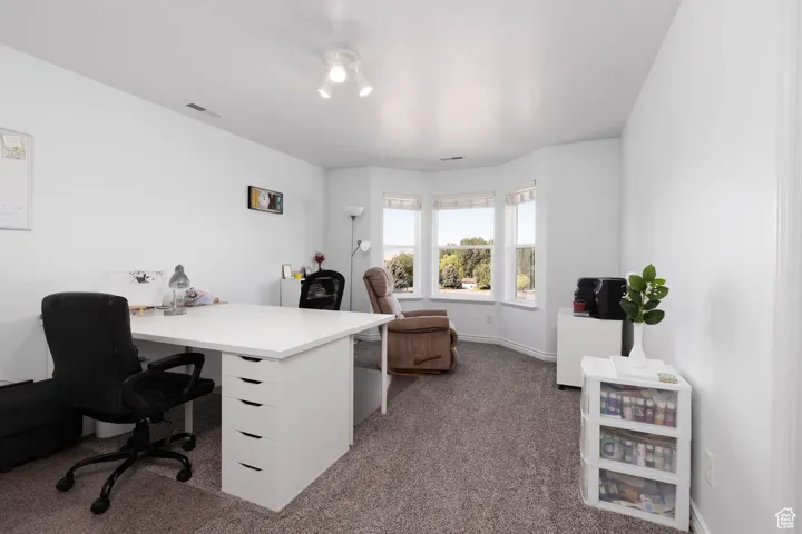 Home office featuring dark carpet and baseboards