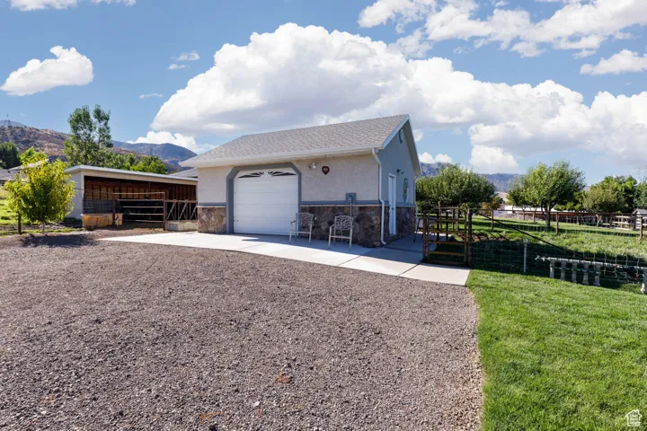 View of home's exterior with stone siding, stucco siding, an outdoor structure, and a mountain view