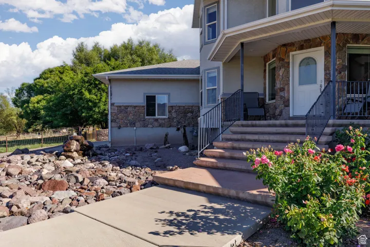 Entrance to property featuring stone siding, stucco siding, and a porch