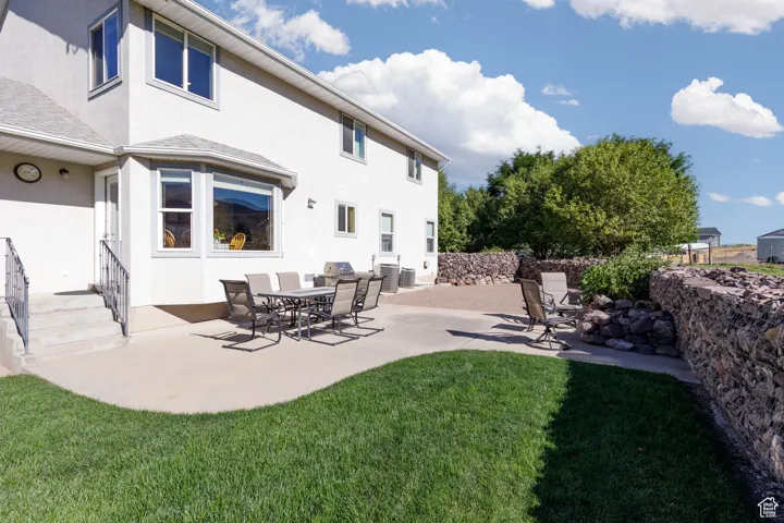Rear view of property featuring stucco siding, a patio area, and a yard