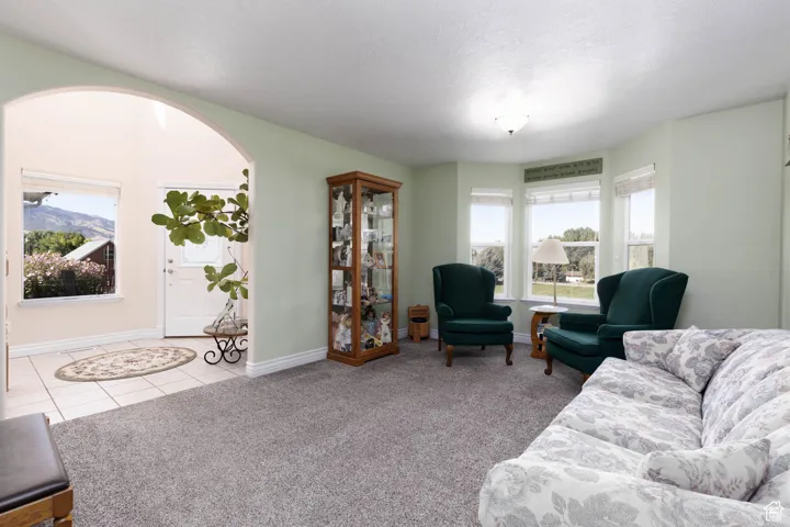 Living room with arched walkways, light tile patterned floors, light colored carpet, and a textured ceiling
