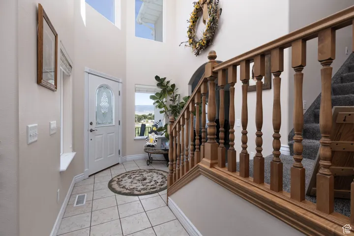 Foyer entrance with stairs, light tile patterned flooring, and a towering ceiling