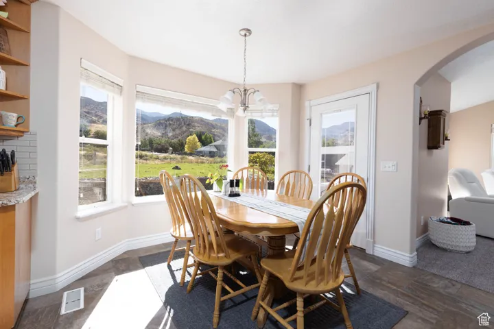 Dining space featuring arched walkways, a chandelier, a mountain view, and dark stone finish flooring
