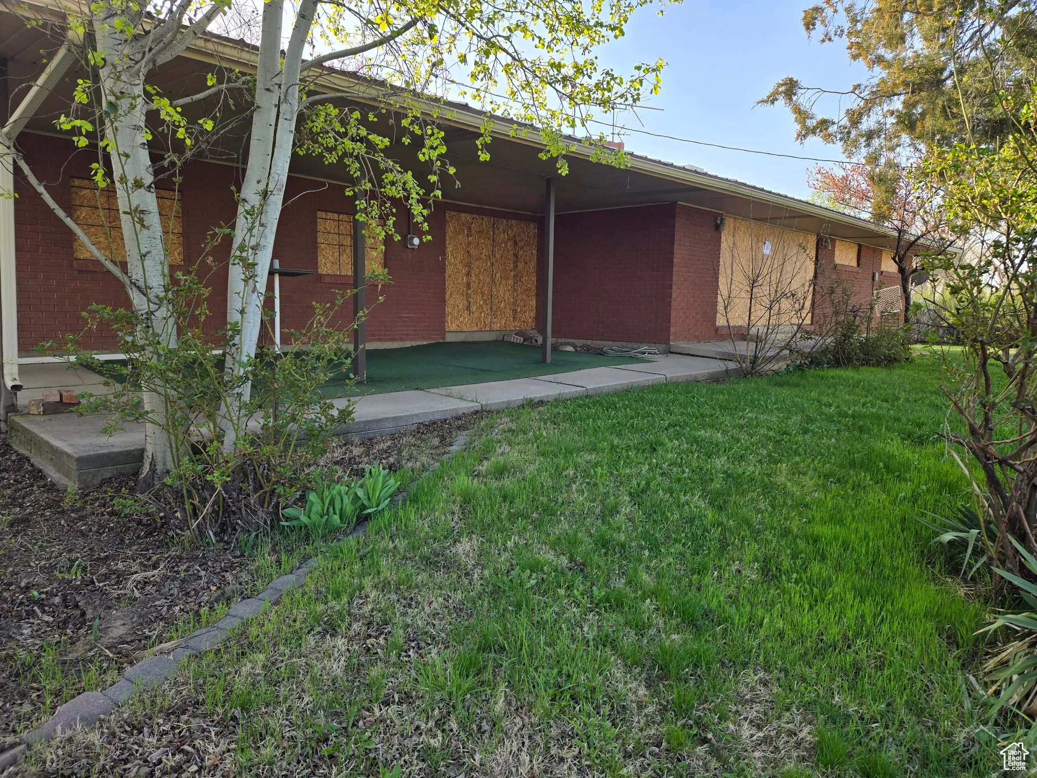 View of side of property featuring brick siding and a lawn