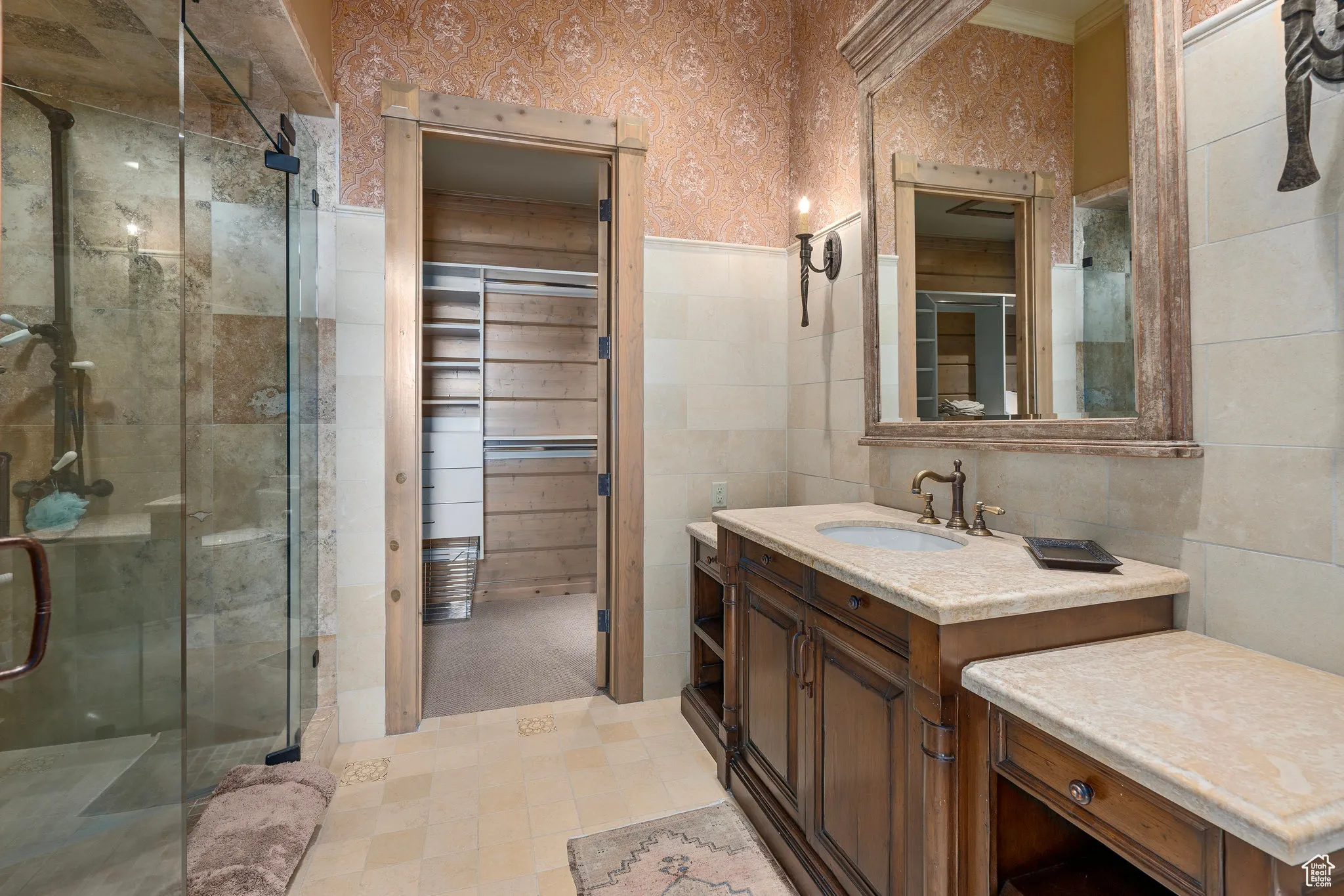 Full bath with a stall shower, wallpapered walls, ornamental molding, vanity, and tile walls
