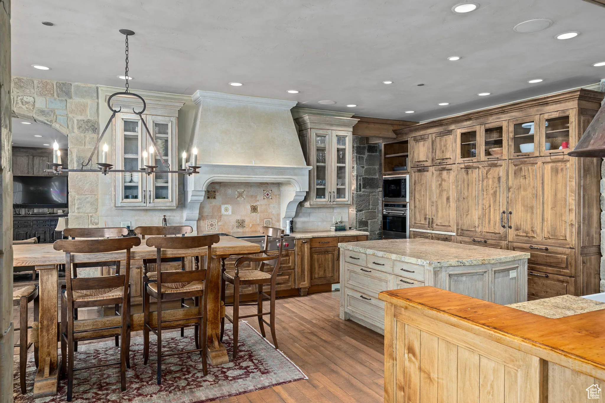 Kitchen with custom range hood, a kitchen island, a notable chandelier, light countertops, and backsplash
