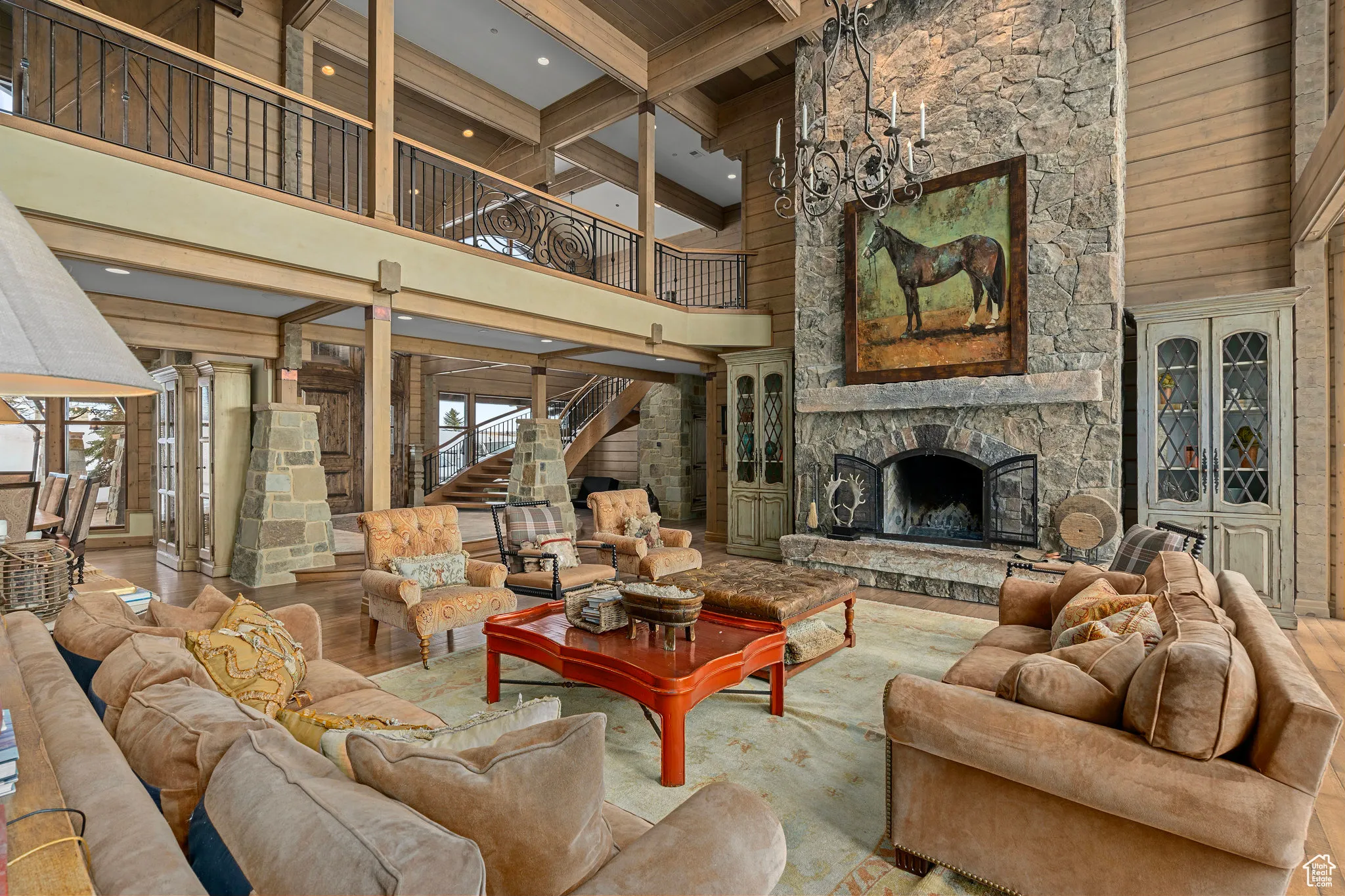 Living room with a fireplace, wooden walls, wood finished floors, beamed ceiling, and stairs