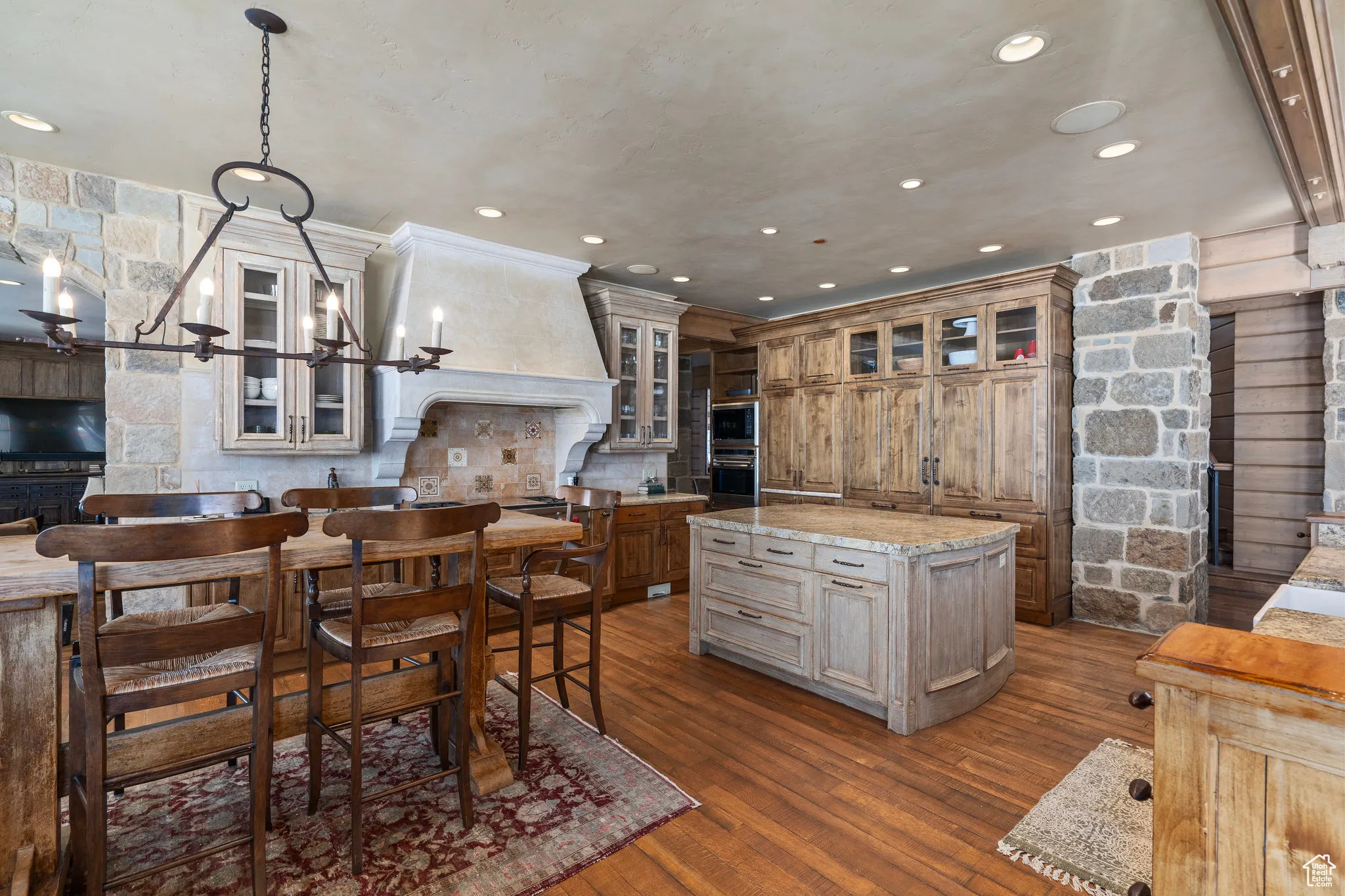 Kitchen with dark wood-style floors, custom range hood, glass insert cabinets, and a center island