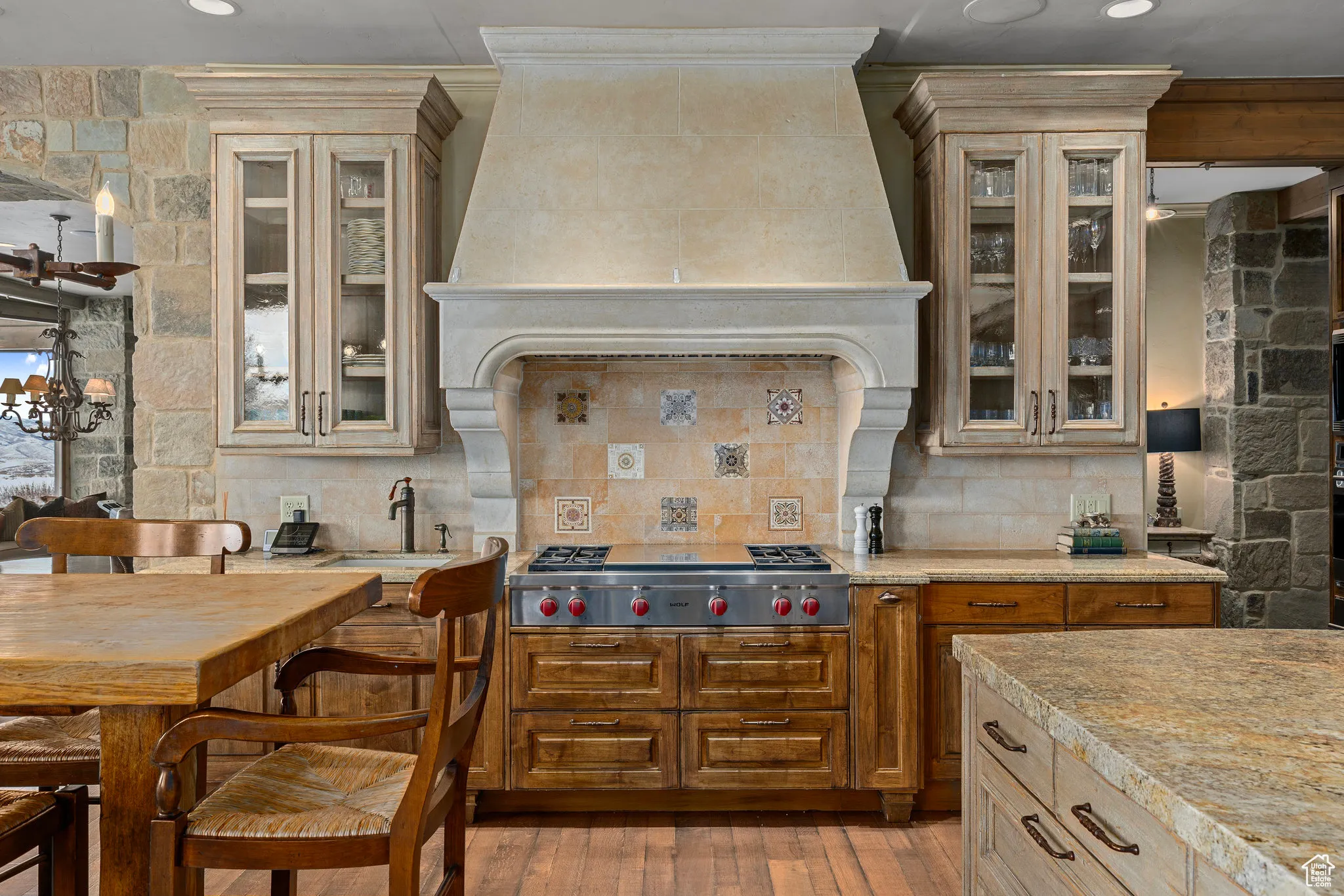 Kitchen with custom exhaust hood, light countertops, stainless steel gas stovetop, light wood-style flooring, and decorative backsplash
