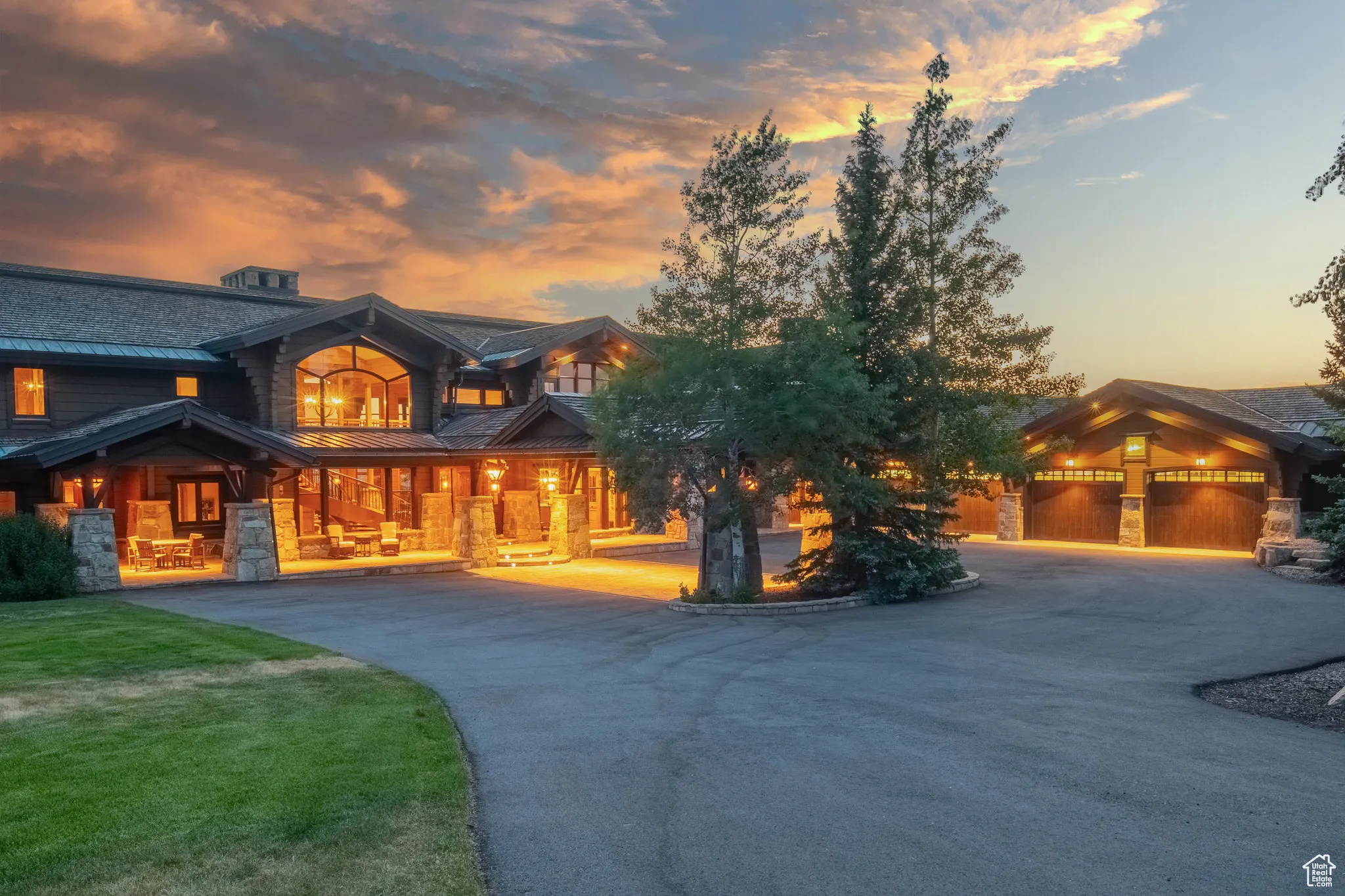 View of front of home featuring a standing seam roof, a metal roof, curved driveway, covered porch, and stone siding