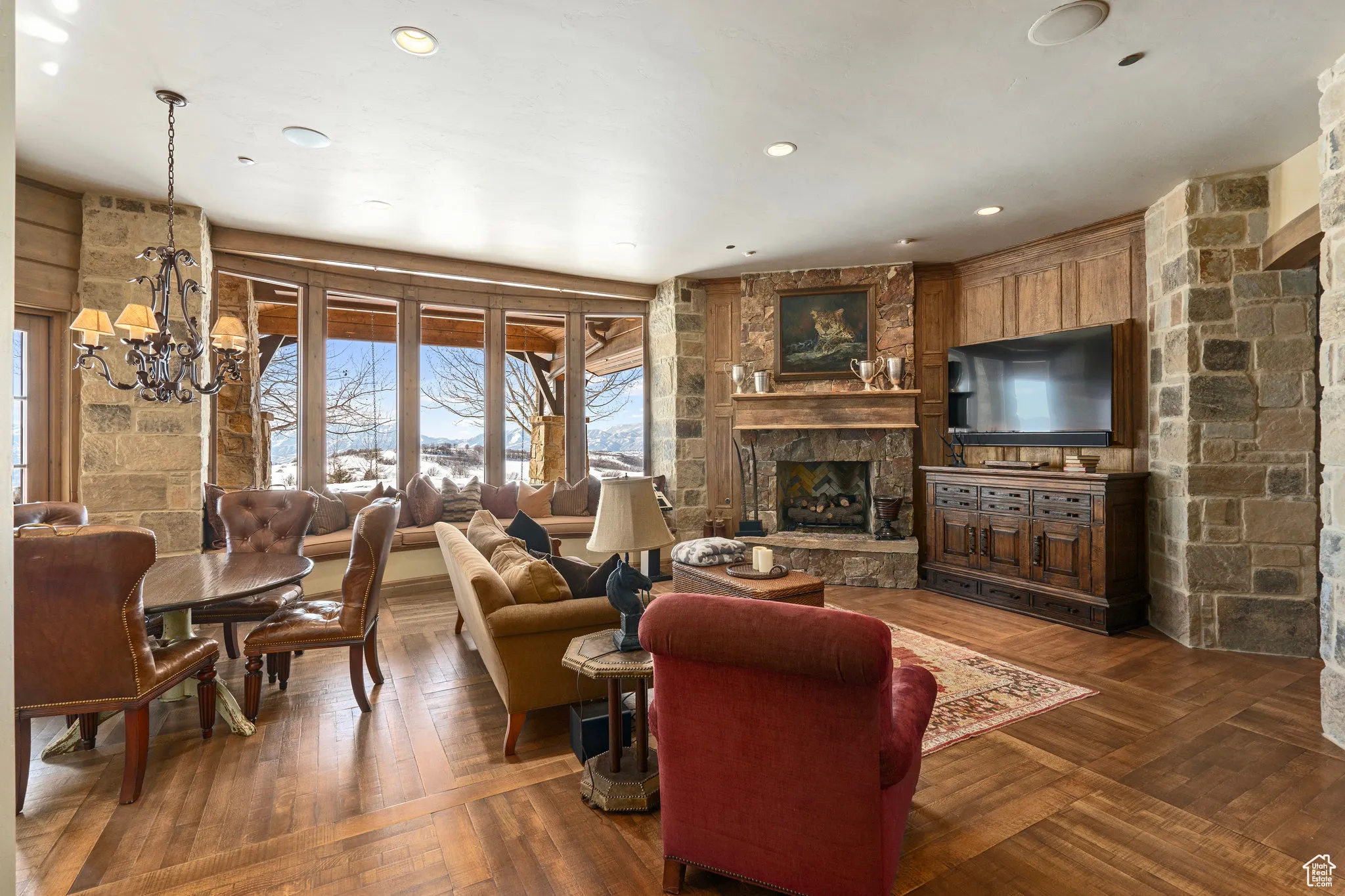 Living area with recessed lighting, an inviting chandelier, wood-type flooring, and a stone fireplace