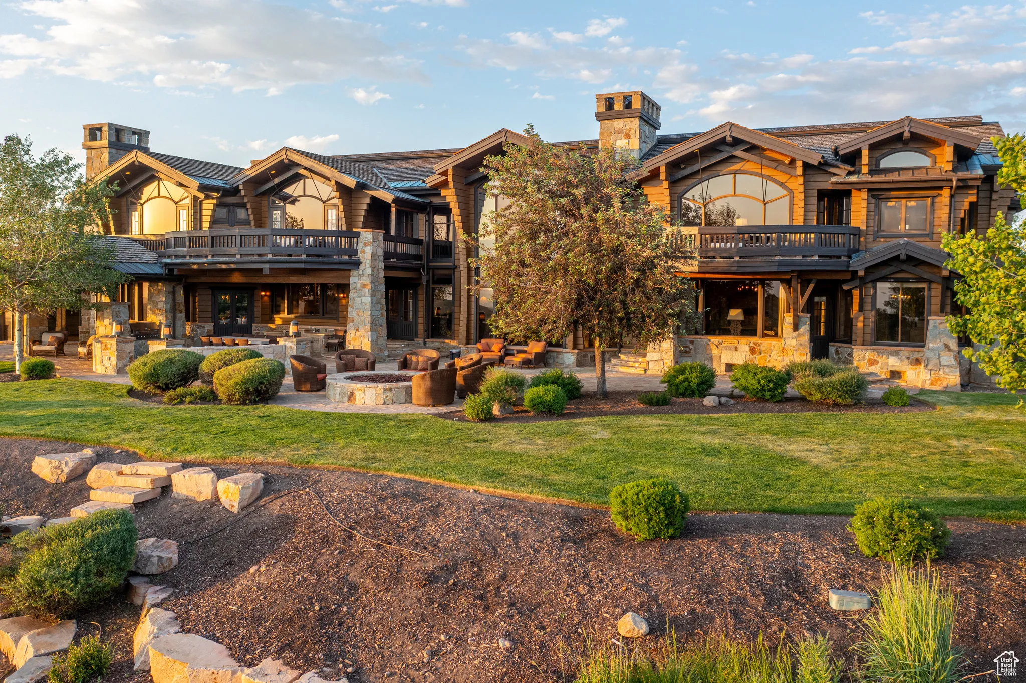 Back of property featuring a chimney, stone siding, and a patio area