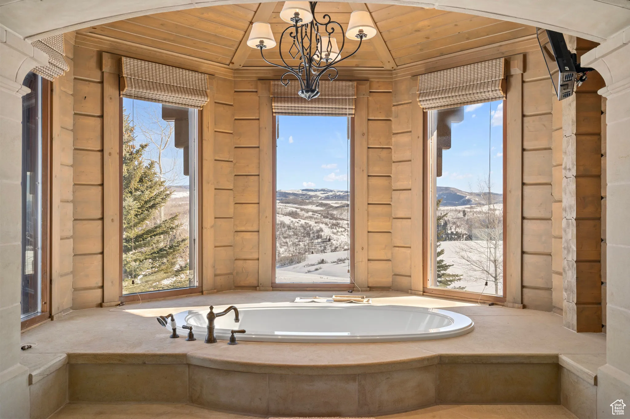 Bathroom featuring a mountain view, a notable chandelier, wood ceiling, and a bath