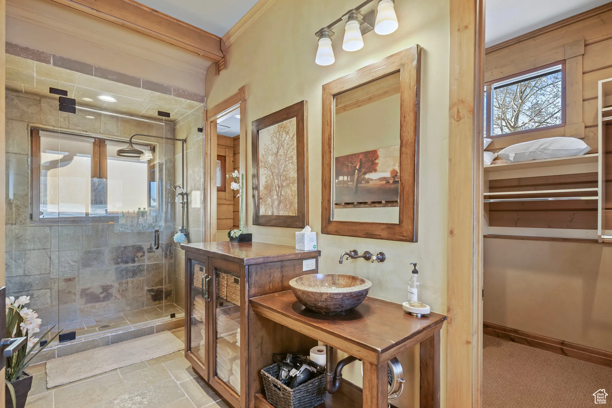 Full bathroom featuring baseboards, ornamental molding, stone tile flooring, a shower stall, and a sink