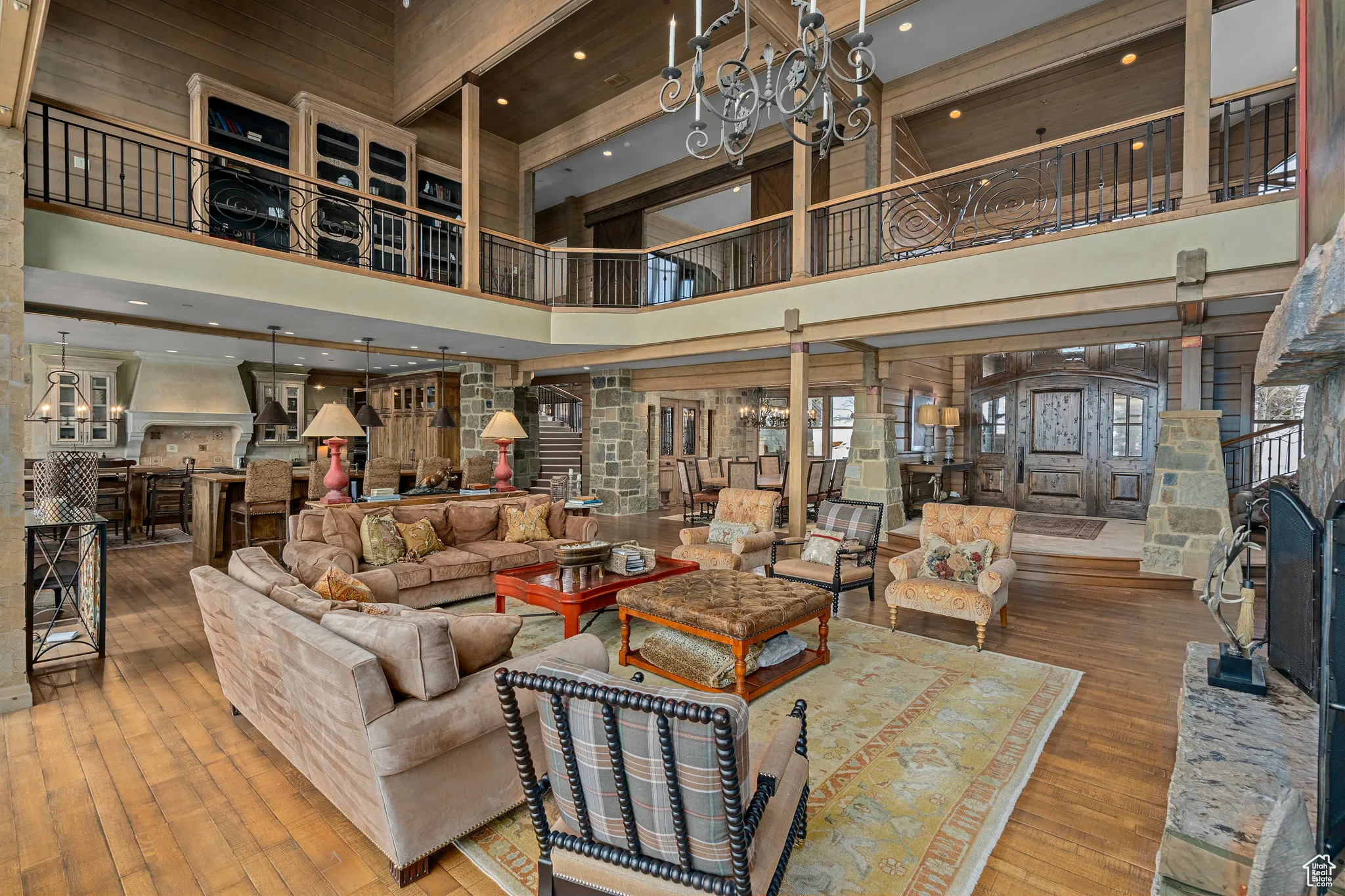 Living area with a towering ceiling, an inviting chandelier, hardwood / wood-style flooring, and ornate columns