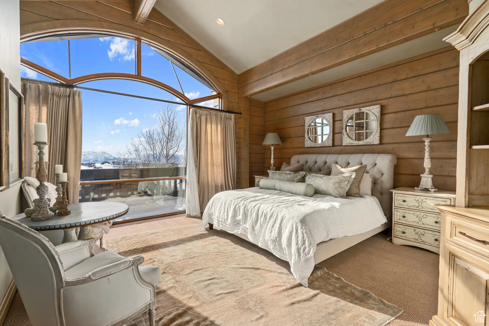 Carpeted bedroom with access to outside, vaulted ceiling with beams, wood walls, and a mountain view