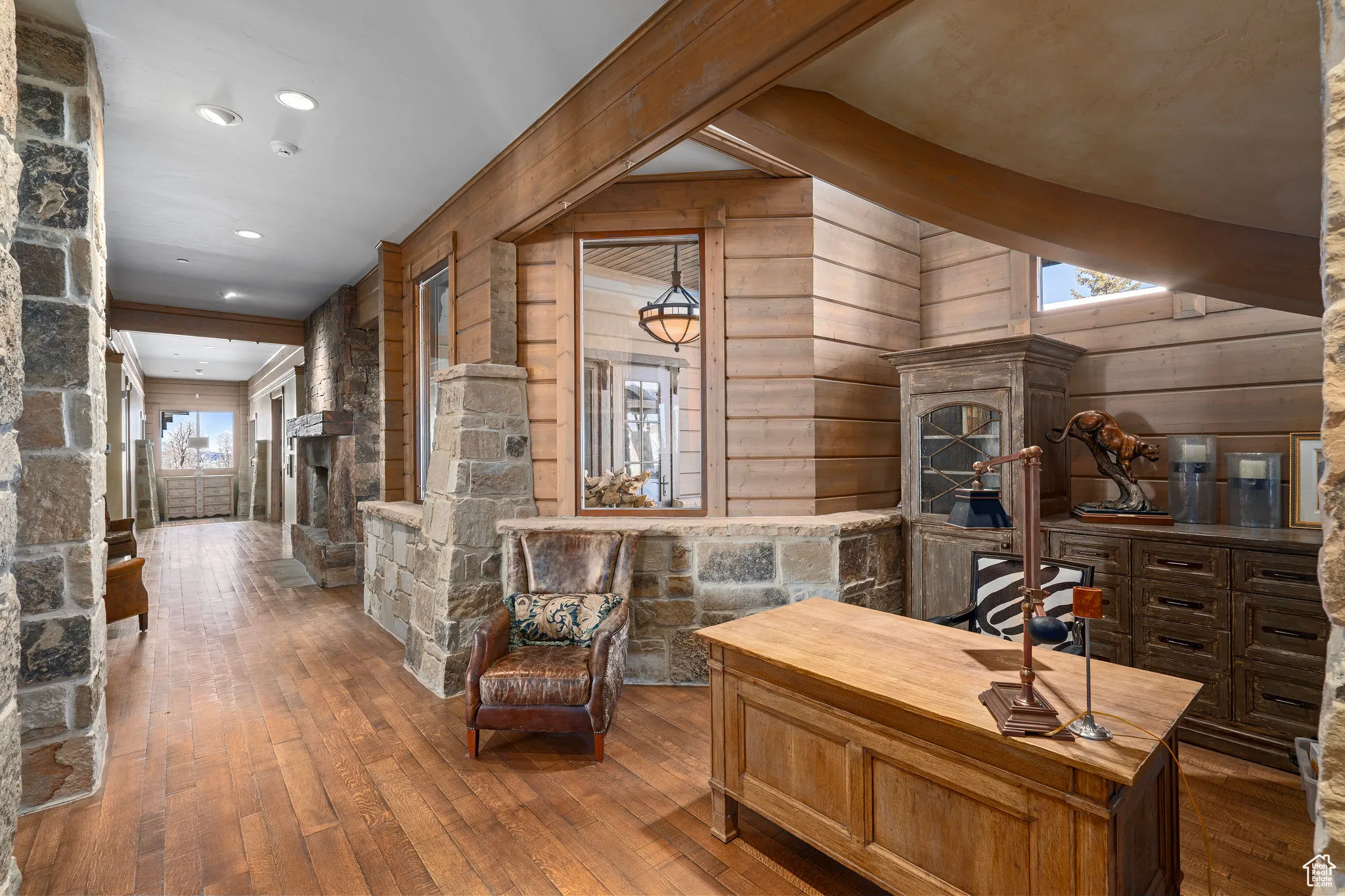 Office space featuring a beamed ceiling, a stone fireplace, and hardwood / wood-style floors